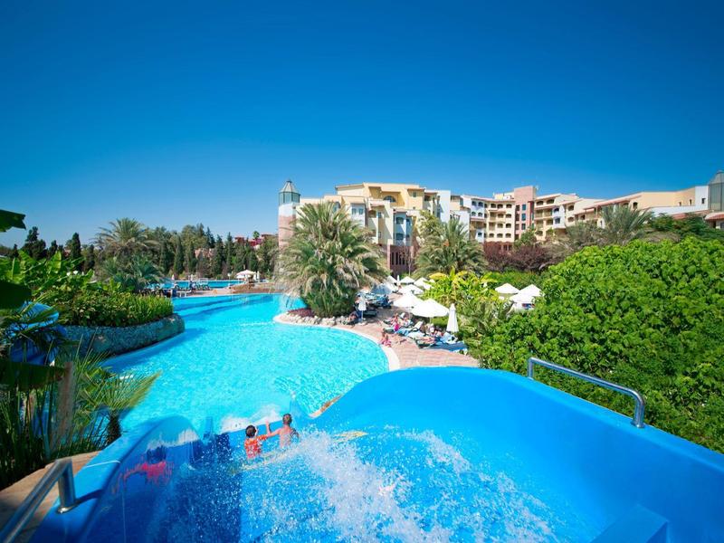 Grande piscina all'aperto in un complesso alberghiero sotto un cielo blu chiaro.