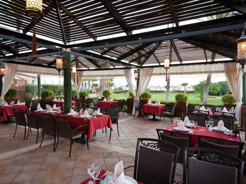 Terrazza coperta di un ristorante con tavoli rossi apparecchiati per gli ospiti.