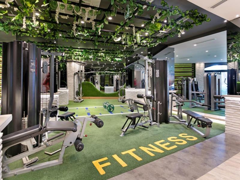 Palestra moderna con attrezzi vari e decorazione vegetale sul soffitto.