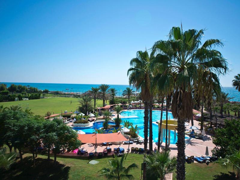 Vista di una piscina con palme e mare sullo sfondo sotto un cielo limpido