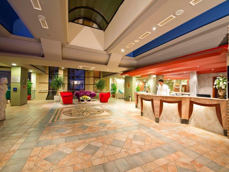 Atrio dell'hotel con reception, area salotto e illuminazione calda.