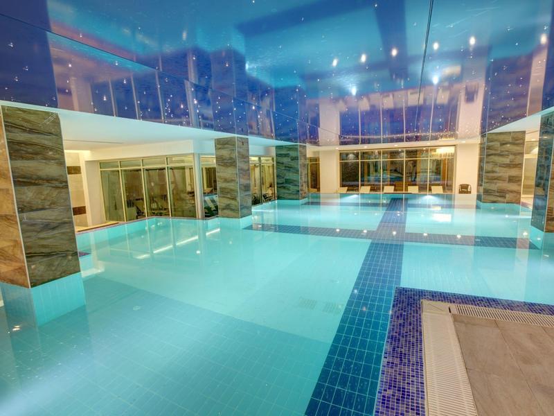 Piscina coperta riscaldata con colonne e illuminazione moderna in un hotel.