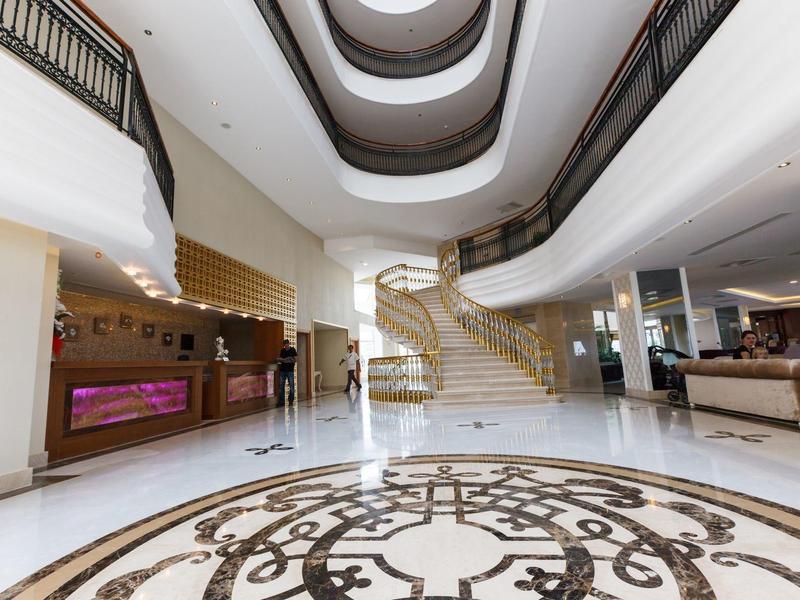 Ampio lobby dell'hotel con scala a chiocciola e area reception elegante in design luminoso.