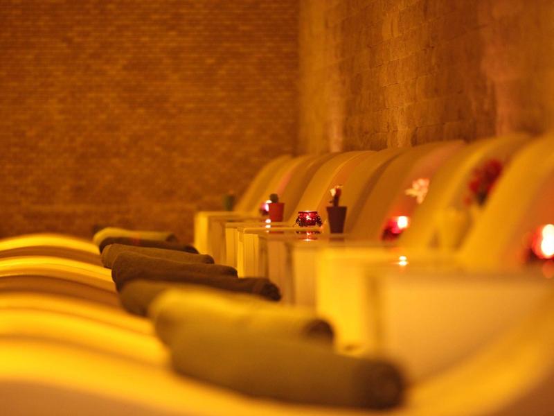 Fila di poltrone spa illuminate con asciugamani e piccole candele.