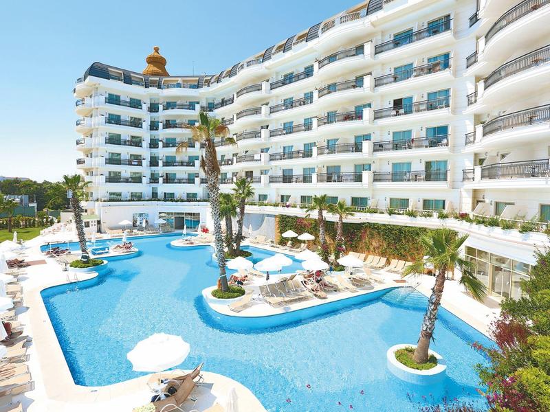 Complesso alberghiero moderno con grande piscina all'aperto, palme e ombrelloni sotto il sole