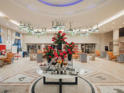 Elegante hall dell'hotel con interno luminoso, disposizione floreale e aree salotto confortevoli.