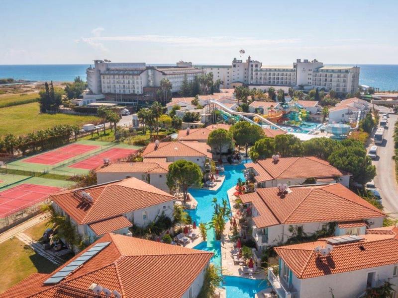 Vista di un grande resort con piscine, campi da tennis e accesso diretto al mare.