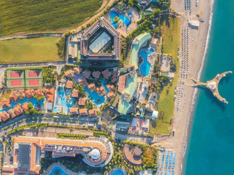 Vista aerea di un resort con piscine, campi da tennis e accesso alla spiaggia