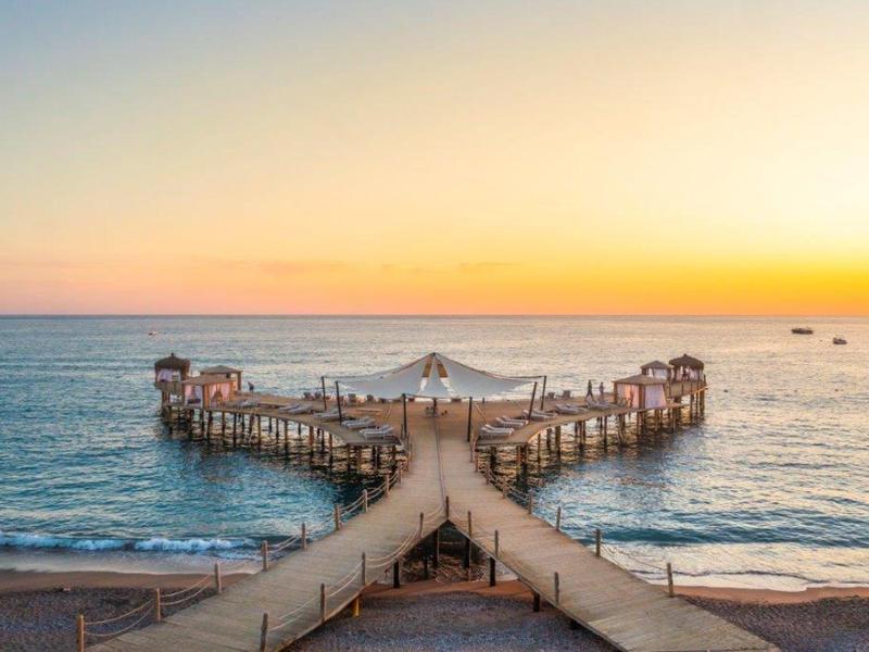 Molo in legno a forma di Y si estende nel mare calmo al tramonto
