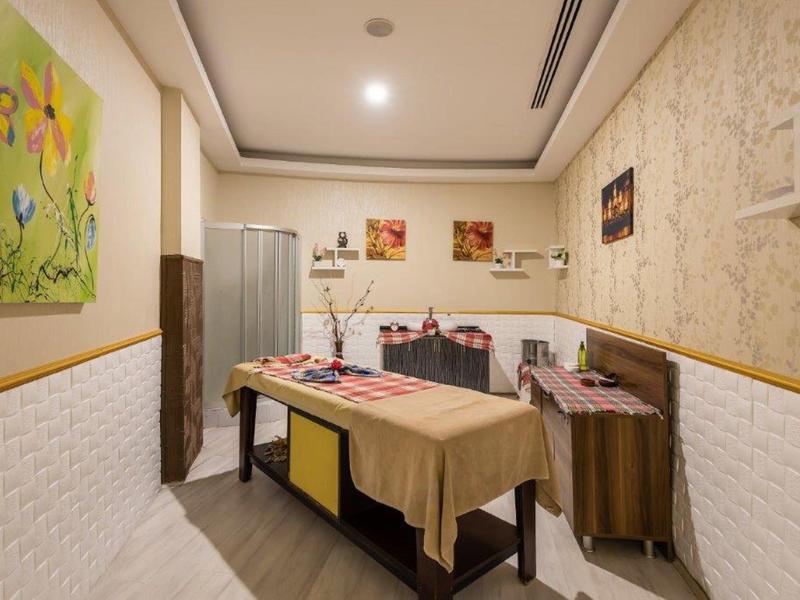 Interno di una stanza benessere accogliente con un lettino da massaggio e decorazioni rilassanti.