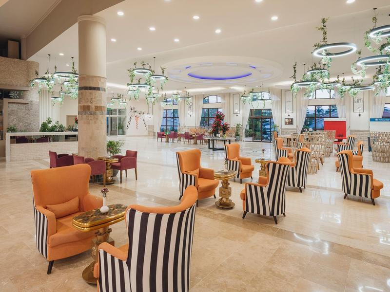 Ampia area lounge dell'hotel con poltrone a motivi e lampadari moderni.
