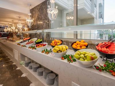 Ein Buffet mit verschiedenen frischen Früchten in weißen Schalen, elegante Beleuchtung im Hintergrund.