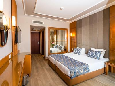 Modern eingerichtetes Hotelzimmer mit Doppelbett, Holzmöbeln und großem Spiegel.