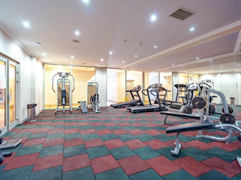 Palestra spaziosa con varie attrezzature per allenamento e pavimento colorato.