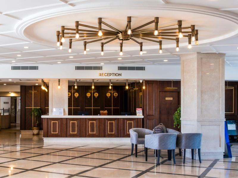 Area reception elegante dell'hotel con mobili in legno, zona salotto e moderno lampadario.