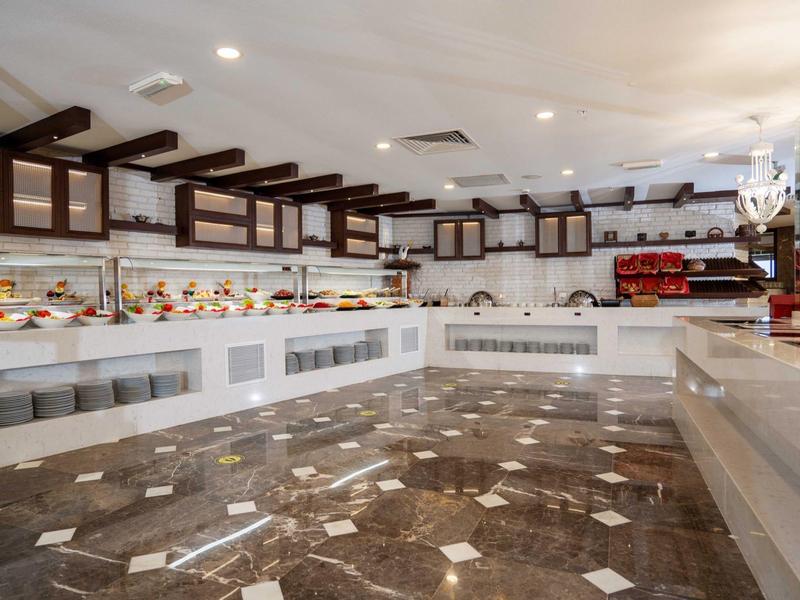 Ampia zona buffet con pavimento in piastrelle di marmo e banconi pieni di cibo in un hotel.