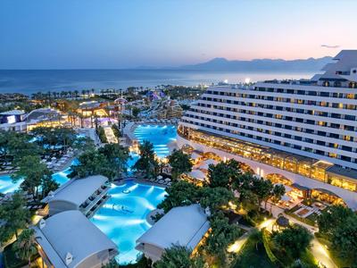Grande resort con più piscine e palme vicino al mare al tramonto.