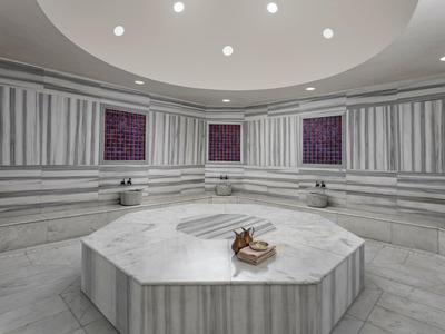 Ampio bagno turco in marmo con piattaforma centrale ottagonale e lucernari circolari.