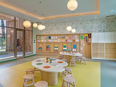 Luminosa sala giochi per bambini con tavoli rotondi, sgabelli, scaffali per libri e luci a globo sospese