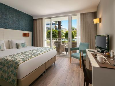 Camera d'hotel moderna con letto matrimoniale, balcone e vista sulle palme