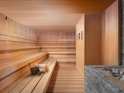 Ampia sauna in legno con panche a più livelli e secchio con mestolo