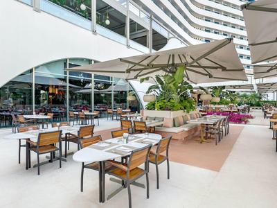 Area ristorante all'aperto con tavoli, ombrelloni e ambiente moderno.