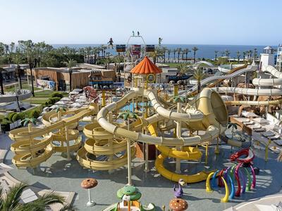 Grande parco acquatico con molte scivoli e giochi d'acqua accanto a un hotel con vista mare.