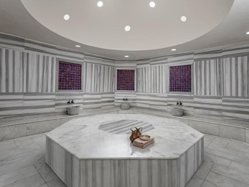 Ampio bagno turco in marmo con piattaforma centrale ottagonale e lucernari circolari.