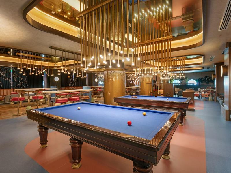 Sala giochi moderna dell'hotel con tavolo da biliardo e luci eleganti.