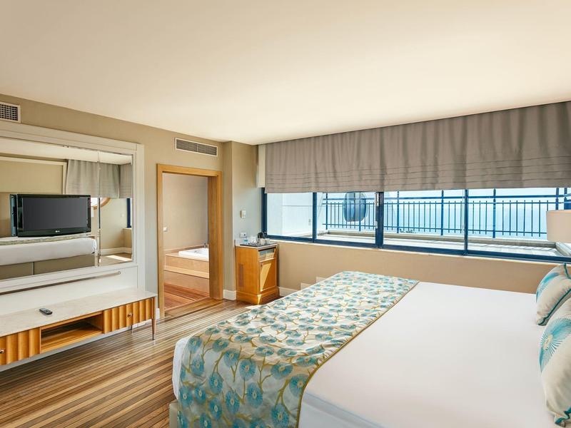 Camera d'hotel moderna con letto grande, vista finestra e pavimento in legno.