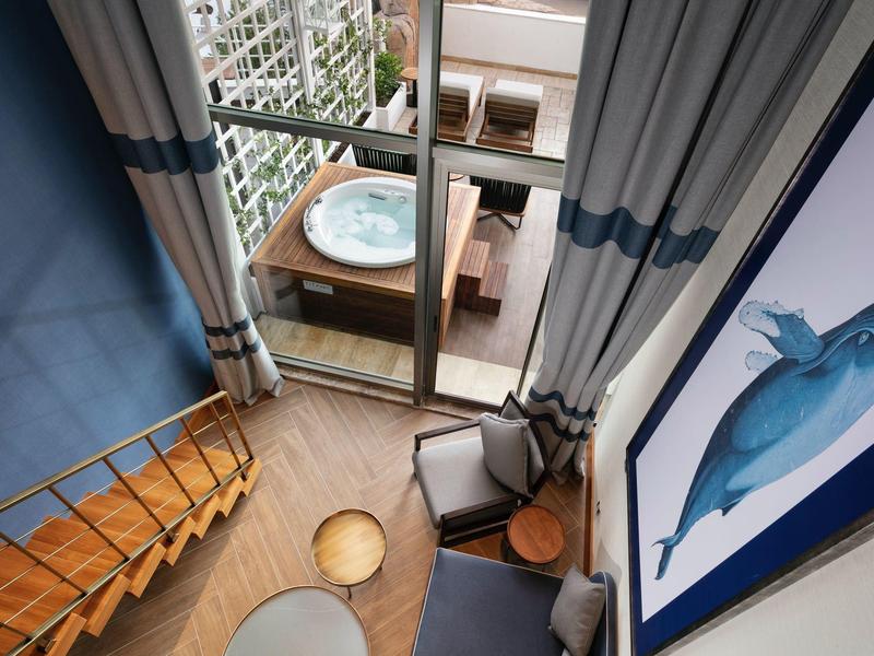 Loft accogliente con scale in legno, area salotto e balcone con vasca idromassaggio e piante.