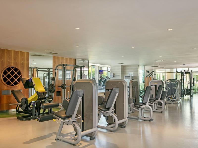 Palestra moderna con varie attrezzature per esercizi e grandi finestre che forniscono luce naturale.