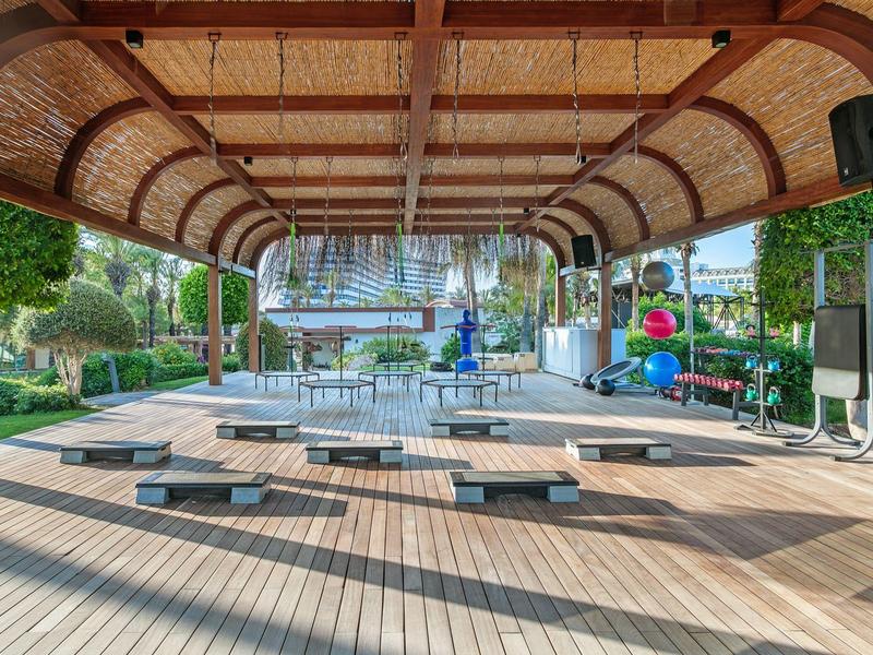 Pavimento in legno con panche sotto un tetto curvo con vista su un lago e vegetazione.