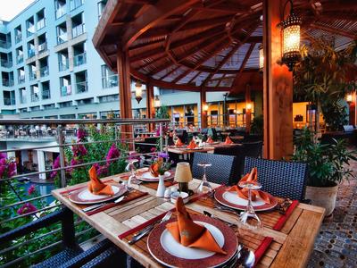 Gemütlicher Gartentisch mit gedecktem Geschirr und orangefarbenen Servietten bei Abendlicht.