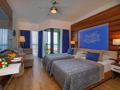 Hotel room with two beds, wooden flooring, blue accents, and a balcony view.