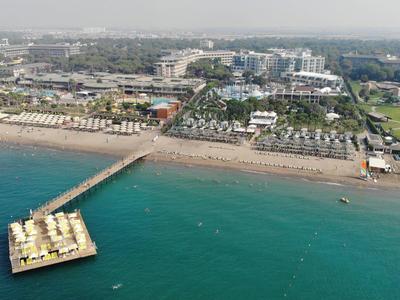 Aerial view of a beach with a pier extending into the sea and buildings in the background.