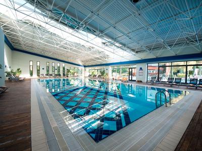 Indoor swimming pool with clear water and large windows letting in natural light.