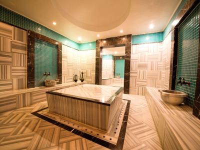 Luxury bathroom with wooden textured tiles, a central marble bathtub, mirrors, and elegant lighting.