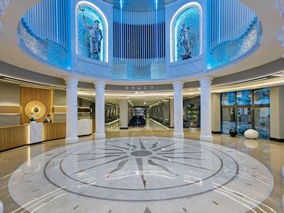 Spacious hotel lobby with circular marble floor, sculptures, and modern lighting.