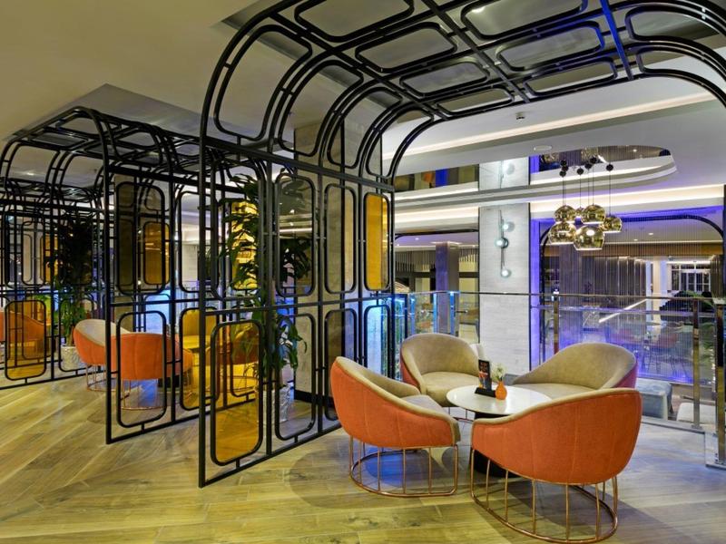 Modern hotel lounge with colorful chairs and black metal frame structures over seating areas.