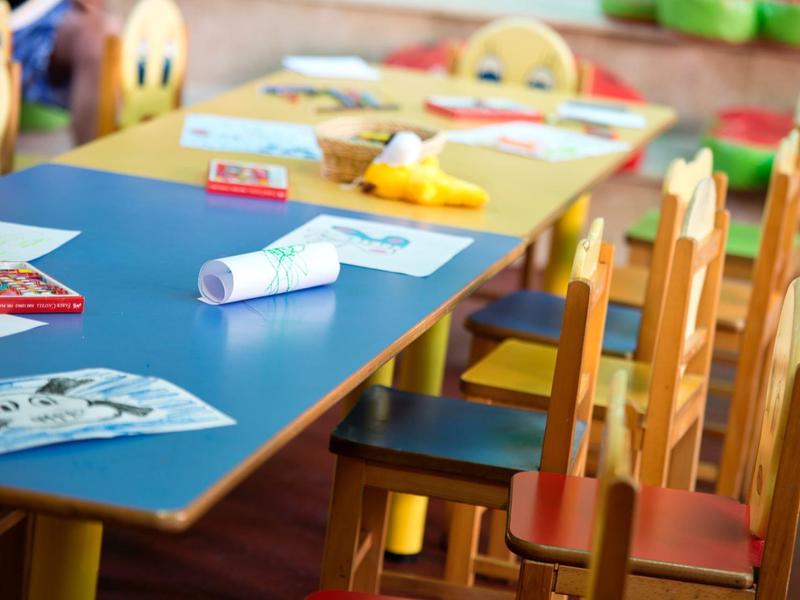 Colorful chairs lined up at a blue table with drawing materials ready for use.