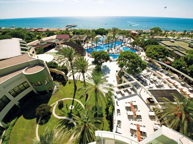 Resort with pools, palm trees, and ocean view under clear sky.