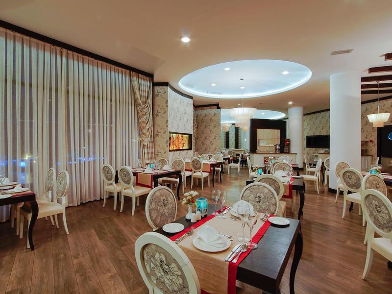 Elegant hotel restaurant with round cushioned chairs, wooden floors, and soft ceiling lights.