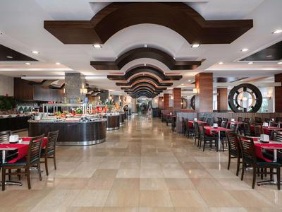 Großer Hotelbuffetbereich mit Tischen, Stühlen und modernem Deckendesign.