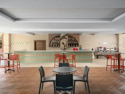 Moderner Hotelbarbereich mit Stühlen und Tischen unter einem überdachten Raum.