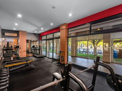 Moderner Fitnessraum im Hotel mit Geräten und großen Fenstern zum Garten.