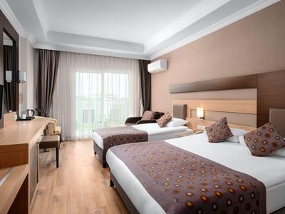 Modernes Hotelzimmer mit zwei Betten, Schreibtisch und Balkon mit Blick nach draußen.