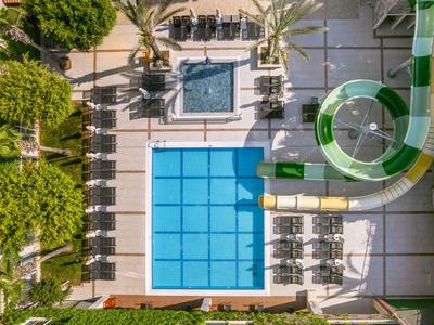Vogelperspektive eines Hotelschwimmbeckens mit Wasserrutsche und Liegestühlen.