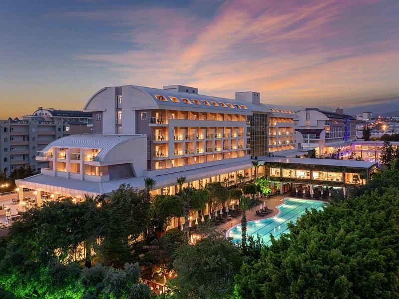 Hôtel moderne avec piscine éclairée et ciel du soir en arrière-plan.