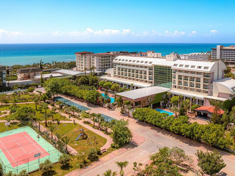 Complexe hôtelier avec terrain de tennis, piscine et vue sur la mer par jour ensoleillé